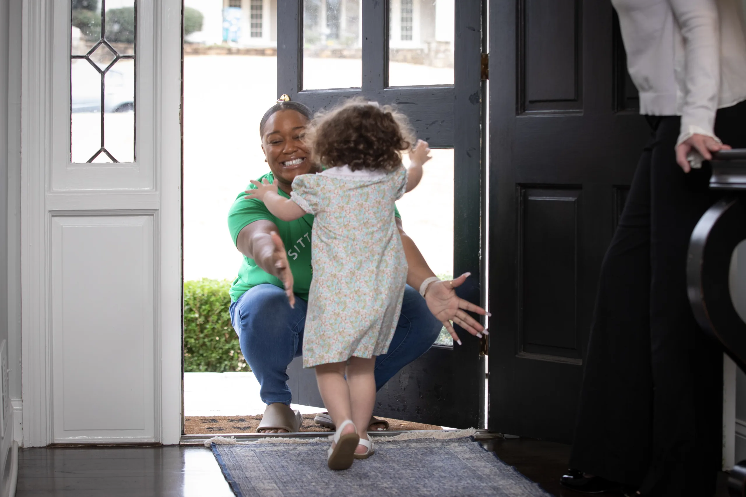 Babysitter and child excitedly greeting each other at door